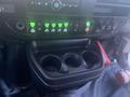 Interior view of a 2017 Chevrolet Express dashboard featuring a set of green indicator lights and a console with three cup holders