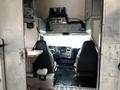Interior view of a 2006 GMC C5000 featuring two black seats a dashboard with controls and a wooden table attached to the wall