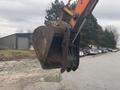 A 2006 Hitachi ZX200LC excavator bucket hanging on an arm with a worn exterior and distinct teeth for digging