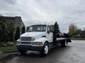 A 2008 Sterling Acterra flatbed truck with a white cab and black flatbed parked on a wet surface