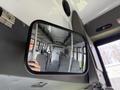 Interior view of a 2010 Ford Econoline showing gray seats and a side mirror reflecting the empty passenger area
