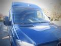 A 2017 Mercedes-Benz Sprinter van with a blue exterior and a distinctive front view showcasing its large windshield and side mirror