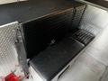 A black bench seat with horizontal stitching positioned in the cabin of a 1995 Freightliner FL70 truck