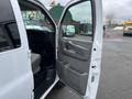 A 2012 Chevrolet Express van with the driver's side door open revealing the interior and driver's seat