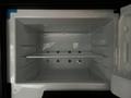 An empty refrigerator interior with a wire shelf and several holes in the back wall