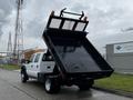 A 2015 Ford F-550 with a raised dump bed revealing a black interior and safety lights on top