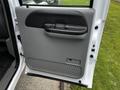 A gray door panel of a 2007 Ford F-550 with a handle and textured footrest at the bottom