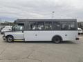 A 2017 Chevrolet Express bus in a light gray color with large windows and a sliding side door