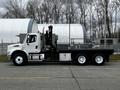 A 2006 Freightliner M2 112 truck in white with a flatbed and hydraulic equipment mounted on the rear