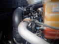 Close-up view of a 2016 International WorkStar 7500 engine featuring various hoses and metal components with visible wear and a coolant reservoir