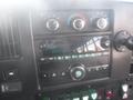 The dashboard of a 2016 Chevrolet Express featuring climate controls a radio display and various buttons and knobs for vehicle operation