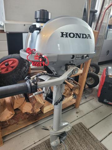 A shiny silver Honda trolling motor with a black handle and red accents on the wiring attached to its side