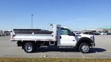 A 2016 Ford F-550 flatbed truck with a white exterior and gray flatbed positioned side view