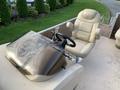 A beige boat helm featuring a steering wheel and a spacious single captain's chair positioned behind a transparent glass windscreen