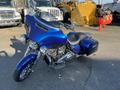 A 2017 Harley-Davidson FLHXS motorcycle in a glossy blue finish with a large windshield and custom seat design