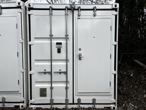 A white 40 foot custom climate controlled storage container with a secure locking system and a door on the right side