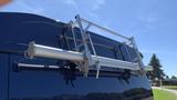 A silver rack mounted on the back of a blue 2013 Ford Econoline designed for carrying equipment or ladders