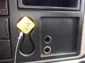 A yellow parking tag attached to a black dashboard panel of a 2015 International 4400 with an empty socket and a circular hole