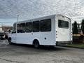 A 2015 Chevrolet Express bus with a white exterior and large windows parked at an angle showcasing its side and rear features