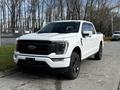 A white 2021 Ford F-150 with a sleek design featuring a black grille and sporty wheels parked prominently on the street