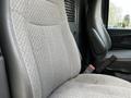 Two gray upholstered seats in the front of a 2015 Chevrolet Express van with seatbelts visible on the side