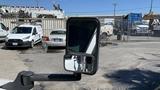 A side mirror of a 2011 Chevrolet Express showing a reflection of another vehicle and the faint outline of the van's body