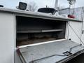 A 2009 Ford F-550 with an open storage compartment revealing two shelves inside and signs of wear and rust along the edges