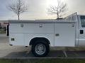 A white 2016 Ford F-350 SD with a utility service body featuring storage compartments on the side and large tires