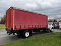 A red 2008 Ford F-750 truck with a boxy cargo area and a white cab parked on grass