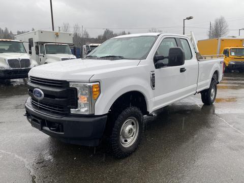 A 2017 Ford F-250 SD in white with a pickup truck design and a crew cab configuration parked on wet ground