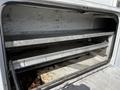 A 2008 Ford F-550 service or utility truck with an open storage compartment featuring metal shelving and a stained floor