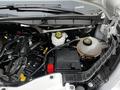 Close-up view of the engine compartment of a 2020 Ford Transit showing various components including brake fluid reservoirs and a battery