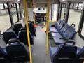 Interior view of a 2017 Chevrolet Express featuring a driver area and multiple blue passenger seats arranged in rows with yellow support poles