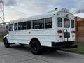 A white 2013 International 4200 school bus with large windows and a rear entry step