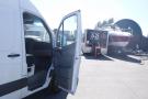 A white 2012 Mercedes-Benz Sprinter van with its driver's side door open, revealing the interior seating area
