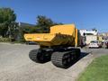 A yellow 2022 TerraMac RT7R tracked carrier with a large dump bed positioned for unloading