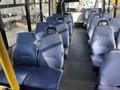 Interior view of a 2018 Chevrolet Express showing rows of blue vinyl seats with high backs and grab handles