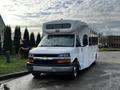 A white 2017 Chevrolet Express van with a high roof and large windows in the front and side