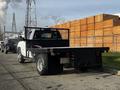 A 2017 Chevrolet Silverado 3500HD with a flatbed and a black mesh safety screen on the back parked on a street