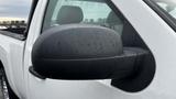 A close-up view of the side mirror of a white 2013 Chevrolet Silverado 1500 with water droplets on its surface