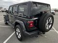 A black 2019 Jeep Wrangler parked with a spare tire mounted on the rear and five-spoke alloy wheels