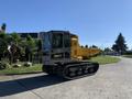 A 2022 TerraMac Tracked Dump with a yellow dump bed and black tracks is parked on a concrete surface with a modern design cab and safety features