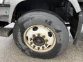 Close-up of a large truck tire mounted on a gray wheel with visible lug nuts and a worn tread pattern