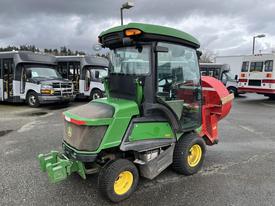 A 2014 John Deere 1585 Terrain Cut zero-turn mower with a green and yellow exterior and a cab, equipped with a red attachment at the back