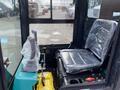 Interior view of a 2024 AGT Industrial QH13R Mini Excavator featuring a driver's seat covered in plastic wrap alongside control levers and foot pedals