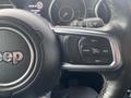 Close-up of a Jeep steering wheel featuring control buttons for cruise control and settings with the Jeep logo prominently displayed