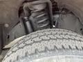 Close-up of the suspension system and tire of a 2011 Ford F-250 SD showing the spiral spring and tread pattern on the tire