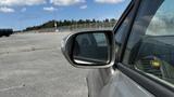 A silver 2006 Honda Fit with droplets of water on its side mirror parked on a lot