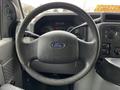Steering wheel of a 2016 Ford Econoline with the Ford logo visible in the center and control knobs on the dashboard in the background