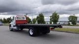 A 2015 International DuraStar 4300 flatbed truck with a white cab and black flatbed parked on a roadway